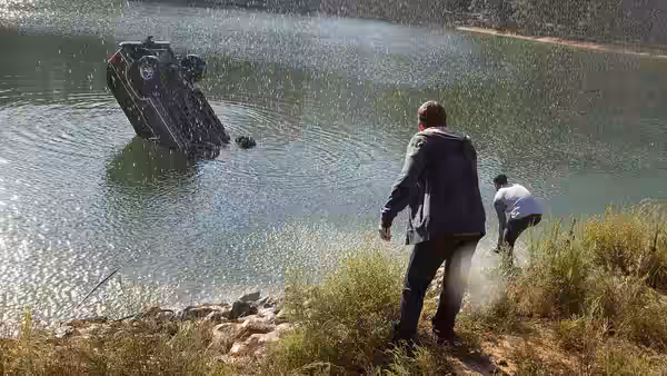 Matt Garetty and Andrew Detmer watch a car rise out of a lake