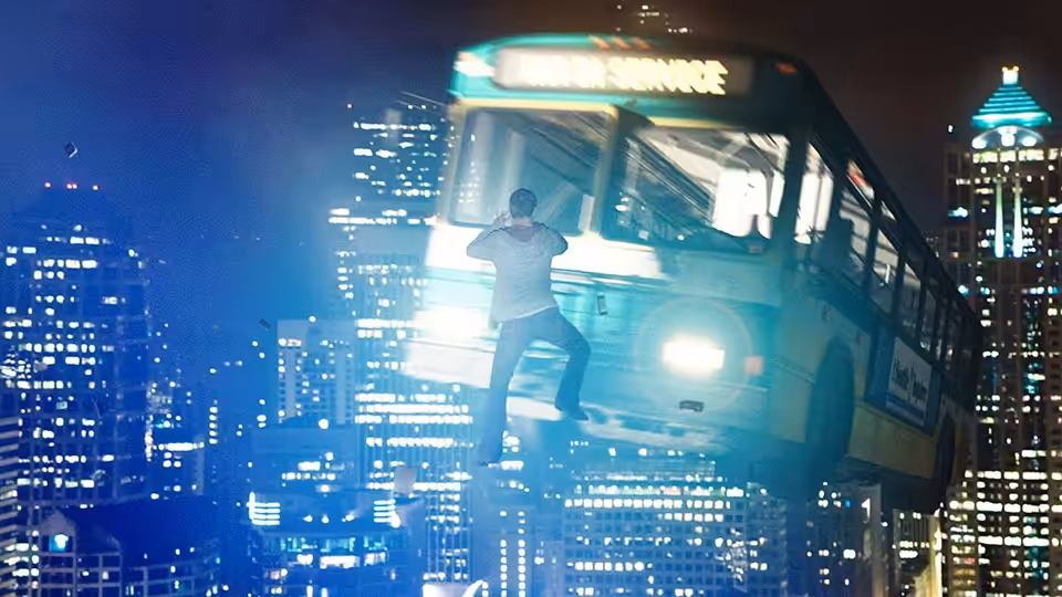 Andrew Detmer clings to the front of a city bus suspended above the streets
