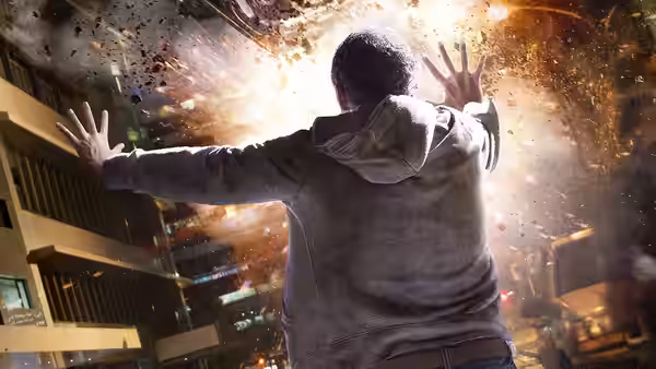 Andrew Detmer raises his hands as debris bursts through the air above a city street