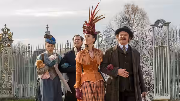 Dr. Watson (John C. Reilly) walks with three companions outside iron gates