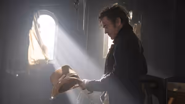 Dr. John Dolittle (Robert Downey Jr.) holding a straw hat in a sunlit room