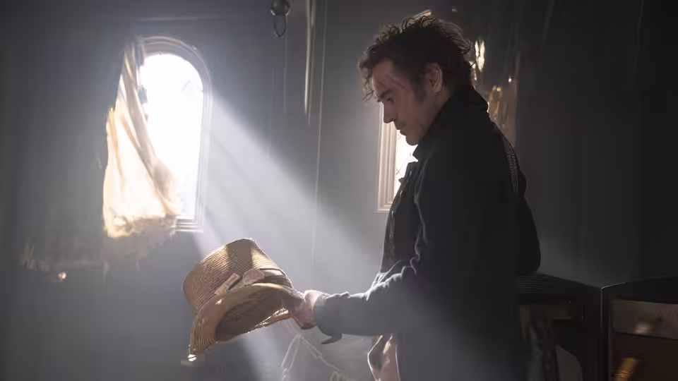 Dr. John Dolittle (Robert Downey Jr.) holding a straw hat in a sunlit room