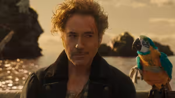 Dr. John Dolittle (Robert Downey Jr.) with a parrot on his shoulder by the sea