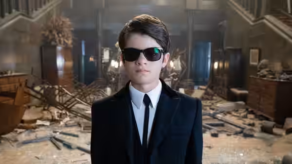Artemis Fowl (Ferdia Shaw) facing forward in a debris-strewn destroyed hall