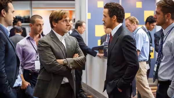 two suited men facing each other in a crowded modern office hallway