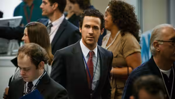 Ryan Gosling walking through a busy trading floor surrounded by colleagues