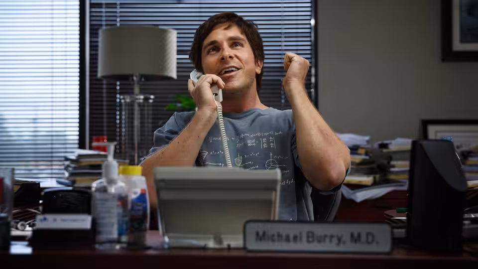 Michael Burry (Christian Bale) raising his fist while on the phone at his desk