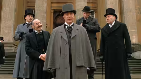 Sherlock Holmes (Michael Caine) stands with several men on the steps of a grand building