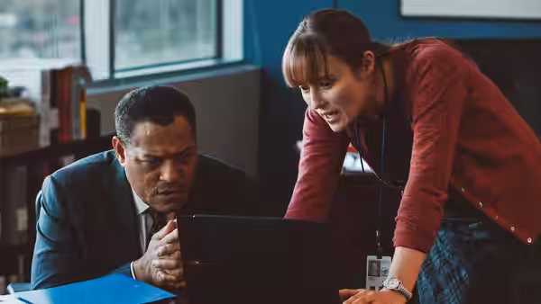Laurence Fishburne and a woman examining a laptop screen