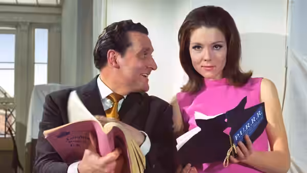 John Steed (Patrick Macnee) and Emma Peel (Diana Rigg) holding books and smiling