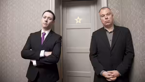Two men standing outside a door with a gold star on it