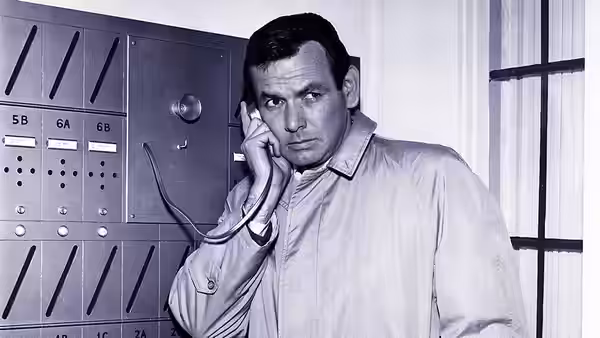 Richard Kimble (David Janssen) speaking on telephone beside a control panel