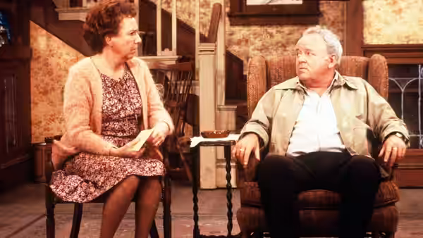 Edith (Jean Stapleton) and Archie (Carroll O'Connor) seated in armchairs