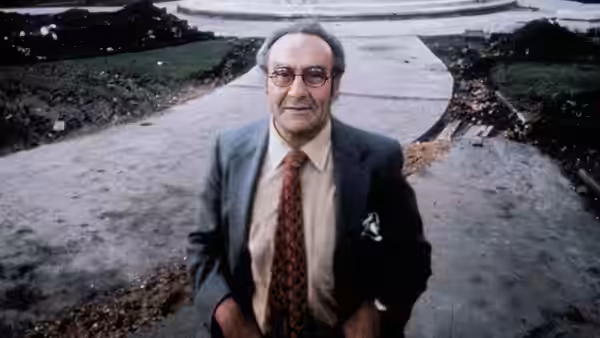 Jacob Bronowski standing on a paved outdoor path in a suit