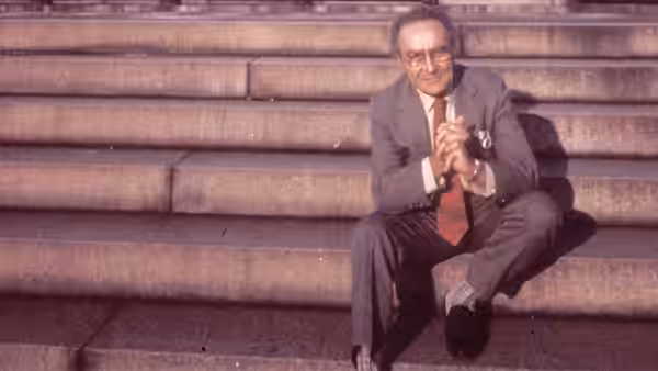 Jacob Bronowski seated on wide stone steps with hands clasped