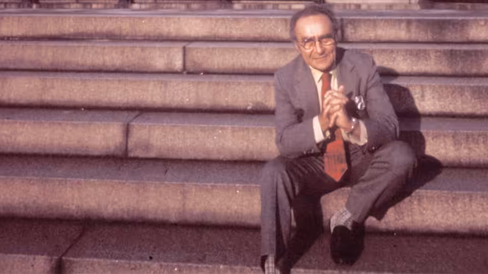 Jacob Bronowski seated on wide stone steps with hands clasped