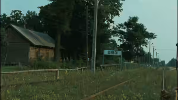 Wooden house and Sobibor sign stand beside quiet road through countryside