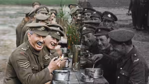 Soldiers laugh and eat from mess tins at a long table