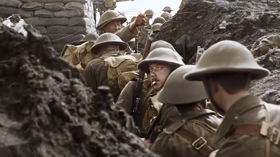 British soldiers in steel helmets move through a narrow, sandbagged trench