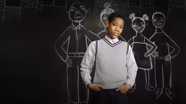 Chris posing in front of a chalkboard covered in drawings