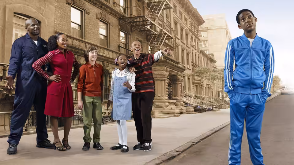Chris in blue tracksuit stands apart from family on a city sidewalk