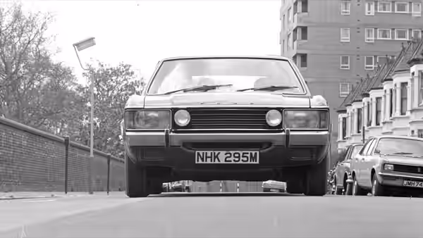 vintage saloon car with number plate parked on a suburban street