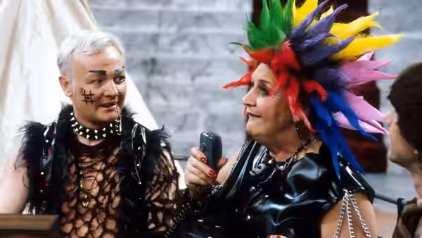 Mrs. Slocombe (Mollie Sugden) in colorful wig holds phone with Miss Brahms
