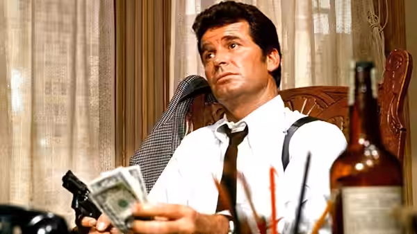 Jim Rockford (James Garner) sits holding cash and a gun while looking upward