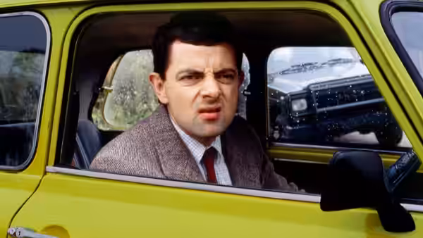 Mr. Bean (Rowan Atkinson) sits in his lime-green car beside a snowy road