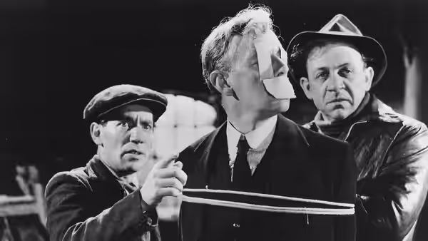 Three men gather around an open case in a workshop