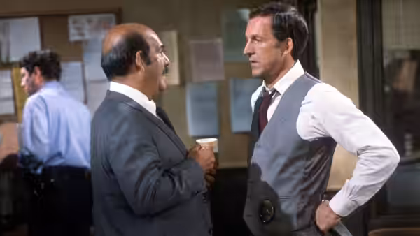 Two men in suits talking inside a police station office