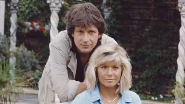Dempsey (Michael Brandon) leaning over Makepeace (Glynis Barber) outdoors