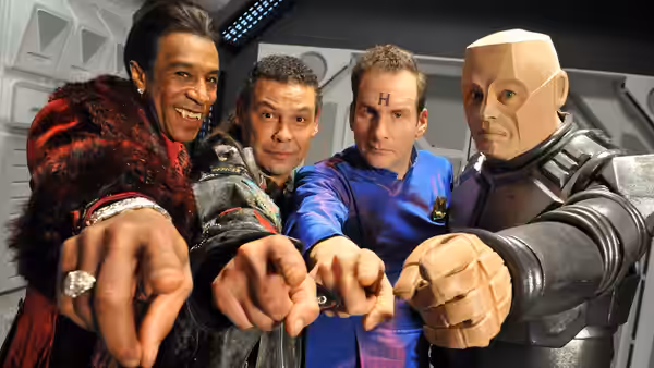 Cat (Danny John-Jules), Lister (Craig Charles), Rimmer (Chris Barrie) and Kryten (Robert Llewellyn) point toward camera