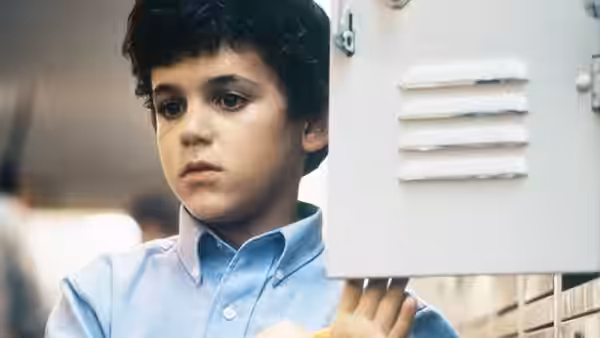 Kevin Arnold (Fred Savage) stands by an open locker looking to the side