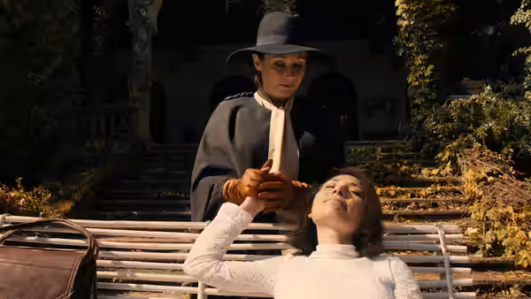 Woman in hat stands on bench holding object above reclining woman