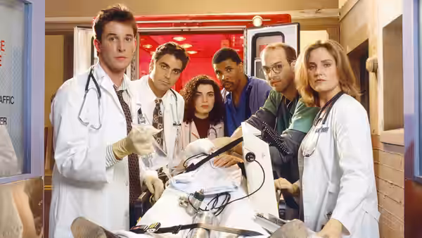 Medical team in white coats gathered around a patient on a gurney in the ER