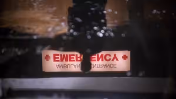 Red emergency sign on a wet dark surface with water droplets and reflections
