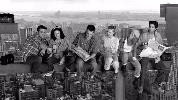 The six friends sit on a skyscraper ledge reading newspapers and magazines overlooking the city