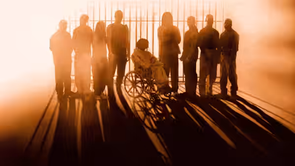 Group of men with one in a wheelchair inside a prison cellblock