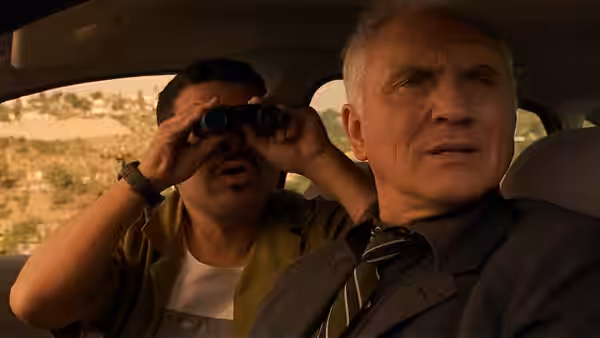 Wilson (Terence Stamp) in a car beside a man with binoculars
