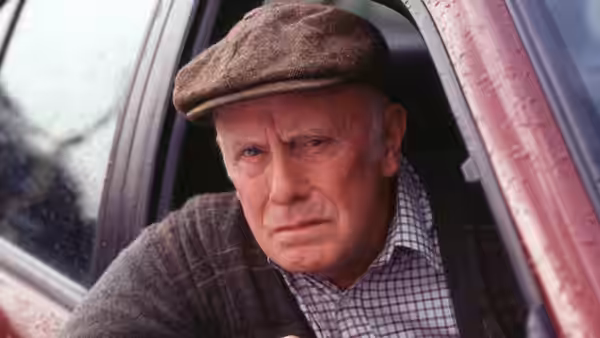 Victor Meldrew (Richard Wilson) looks out through an open car window wearing a cap