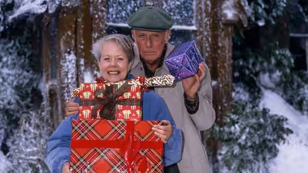 Victor Meldrew (Richard Wilson) and Margaret Meldrew (Annette Crosbie) hold wrapped Christmas gifts in snow