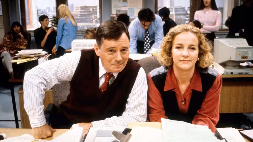 Henry Davenport (David Swift) and Alex Pates (Haydn Gwynne) seated at an office desk