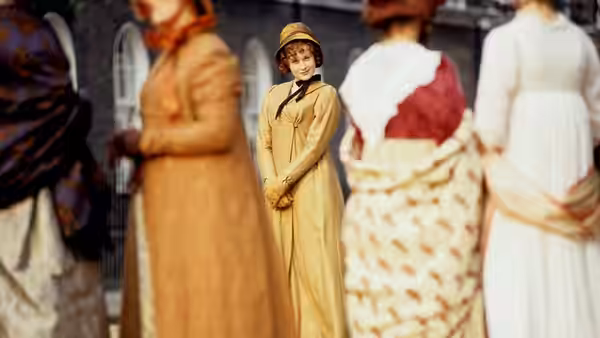 Women in period dresses stand together in an outdoor courtyard