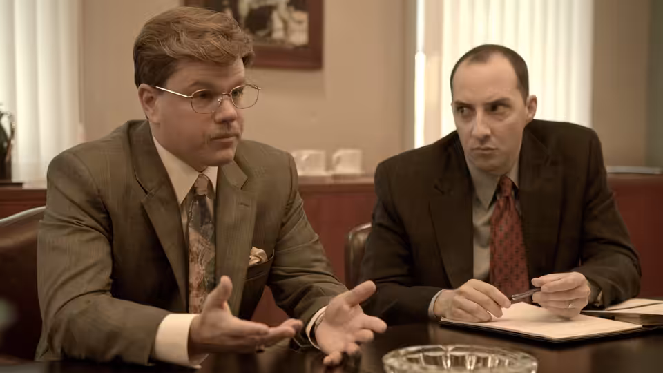 Mark Whitacre (Matt Damon) gesturing with both hands while seated at a table