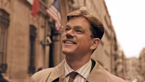 Mark Whitacre (Matt Damon) smiling upward on a city street with flags behind him