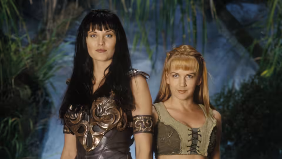 Xena (Lucy Lawless) and Gabrielle (Renée O'Connor) standing together in lush greenery