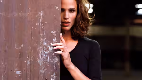Woman with brown hair peers around the edge of a wooden door