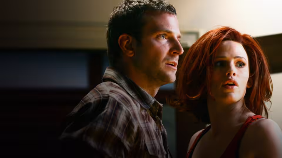 Man and red-haired woman stand close together looking to the side