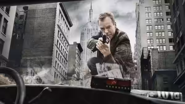 Jack Bauer (Kiefer Sutherland) aiming a gun from inside a vehicle in the city